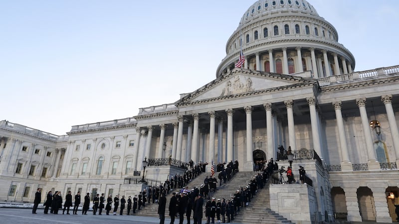 A joint services military body bearer team carries the flag-draped casket of former President...