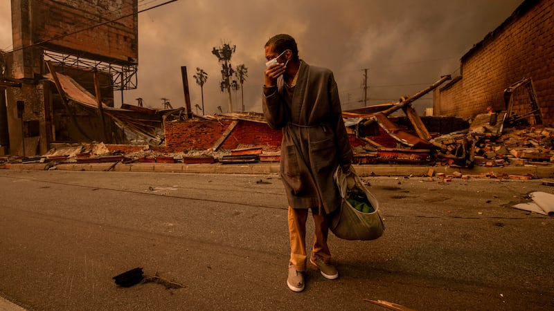 A man walks past a fire-ravaged business after the Eaton Fire swept through Wednesday, Jan. 8,...